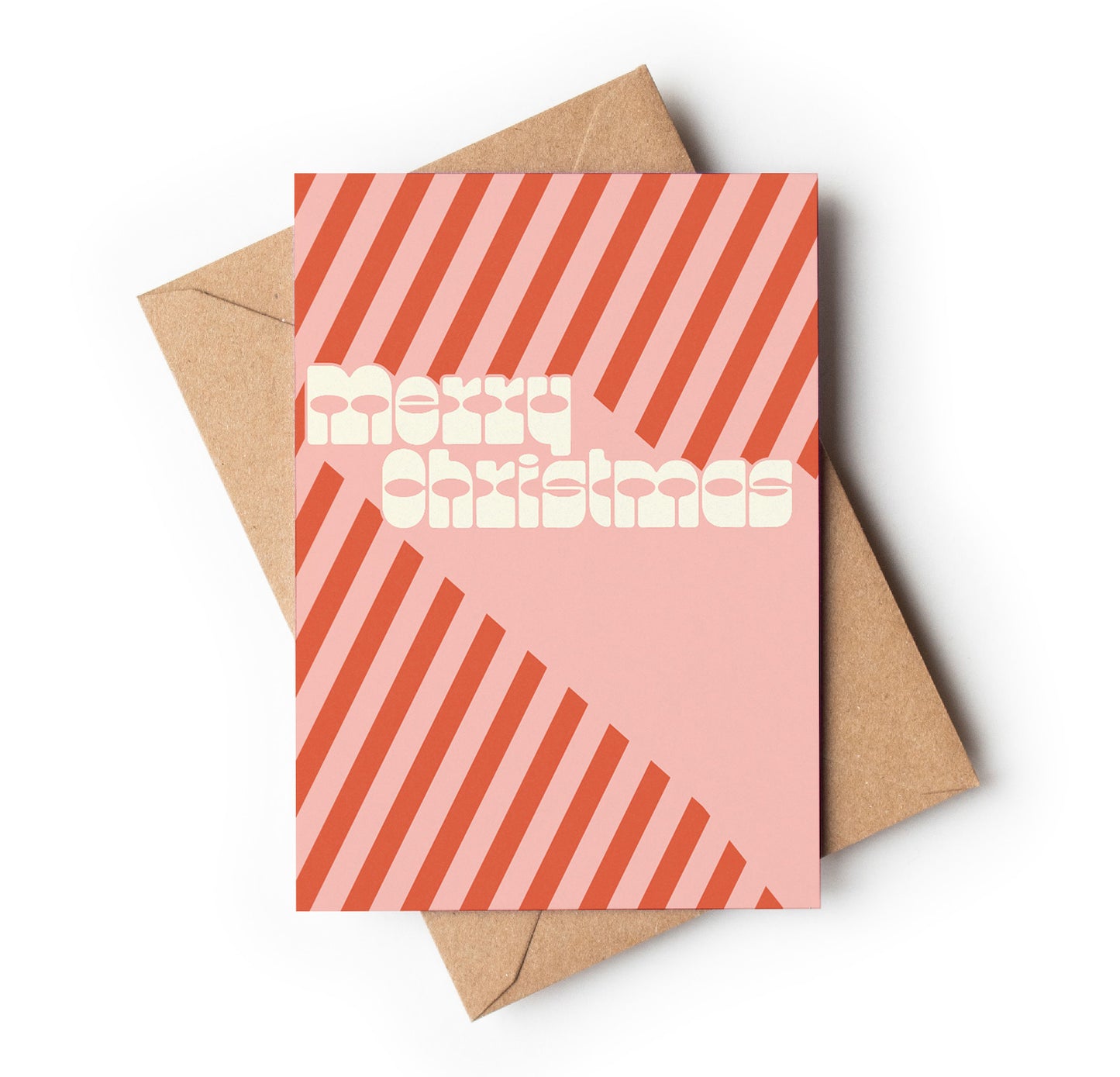 Pink Christmas card with red stripes and 'Merry Christmas' text, placed on a brown envelope.