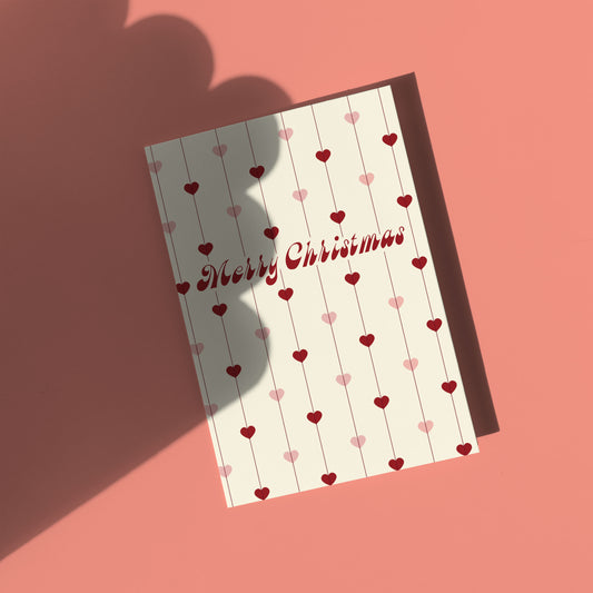 Greeting card with 'Merry Christmas' text and heart patterns on a pink background