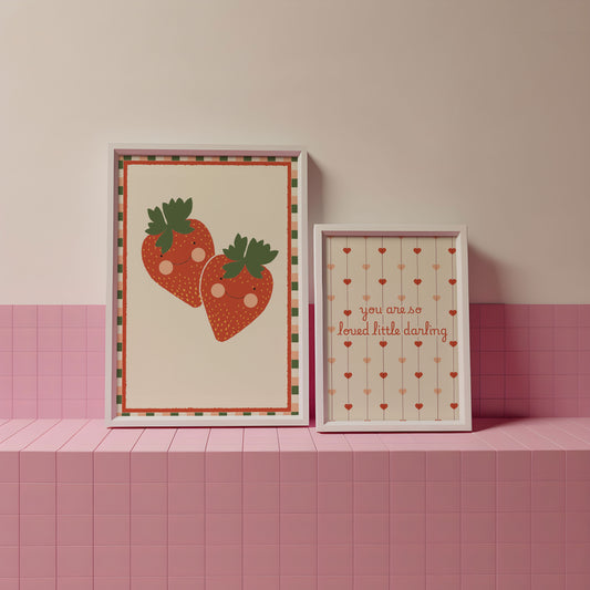 Two framed prints on a pink tiled surface with a neutral wall background