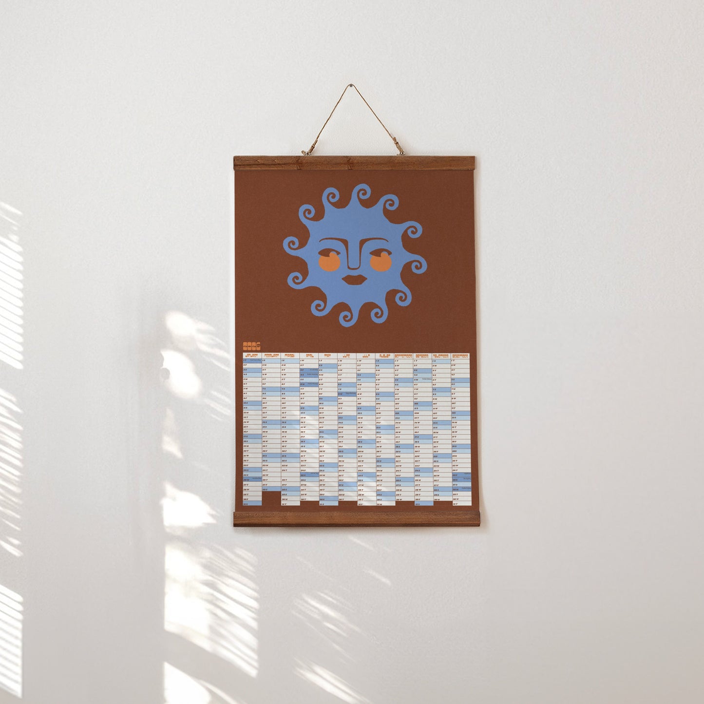 Decorative wall hanging with a sun design on a brown background, hanging on a white wall.