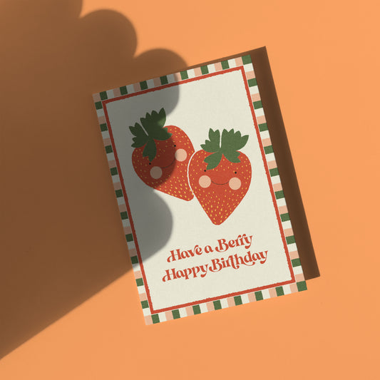 Greeting card with cartoon strawberries and 'Have a Berry Happy Birthday' text on an orange background