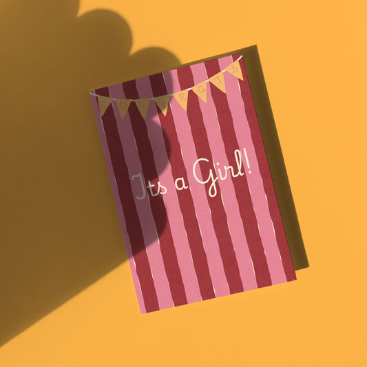 Striped card with 'It's a Girl!' text on a yellow background