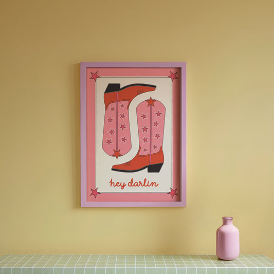 Framed artwork of red boots on a yellow wall above a green tiled table.