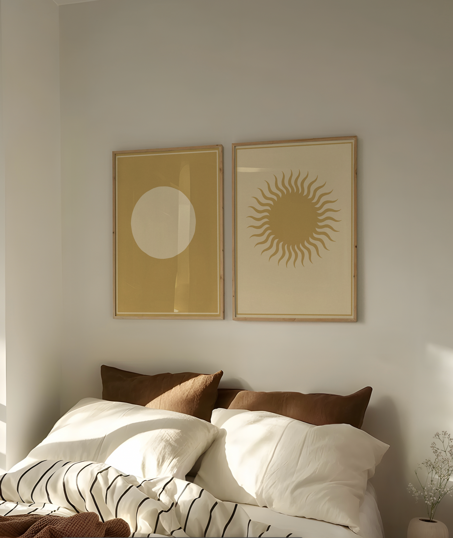 Two framed abstract artworks on a wall above a bed with pillows.