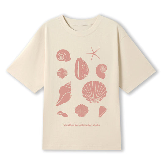 Beige t-shirt with pink shell designs and text on a white background